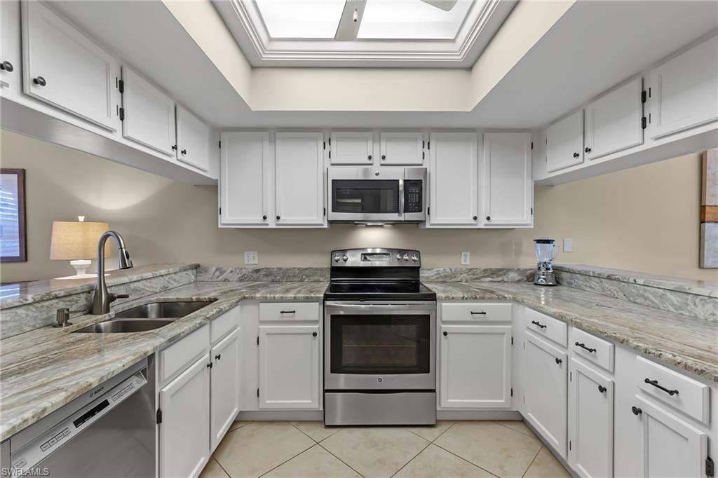 5899 Chanteclair Drive, Unit 214 Naples, FL 34108 - Photo 4 of 24 a kitchen with granite countertop white cabinets white stainless steel appliances and a sink