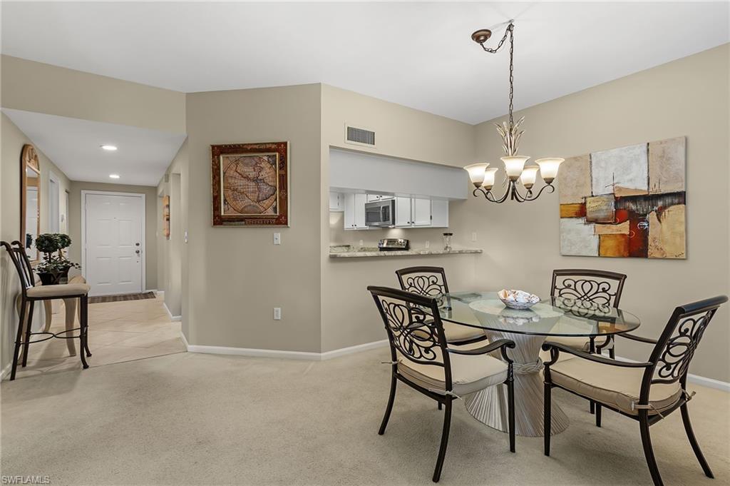5899 Chanteclair Drive, Unit 214 Naples, FL 34108 - Photo 8 of 24 a view of a dining room with furniture and chandelier