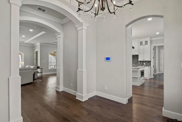 a view of a hallway with wooden floor a glass door and a kitchen