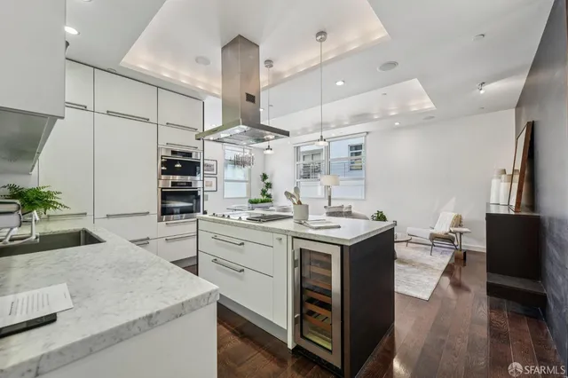 a kitchen with stainless steel appliances kitchen island granite countertop a sink a stove and a wooden floors