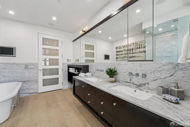 a spacious bathroom with a double vanity sink a large mirror and a shower