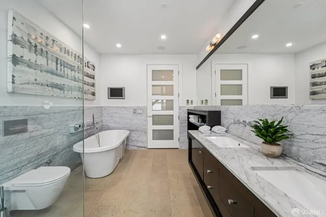 a spacious bathroom with a double vanity sink a large mirror and a toilet