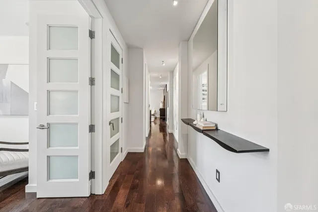 a hallway with white cabinets and wooden floor