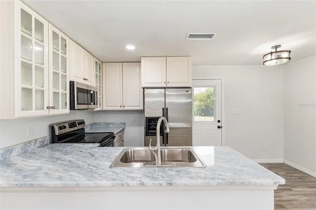 a kitchen with kitchen island a counter top space cabinets and stainless steel appliances
