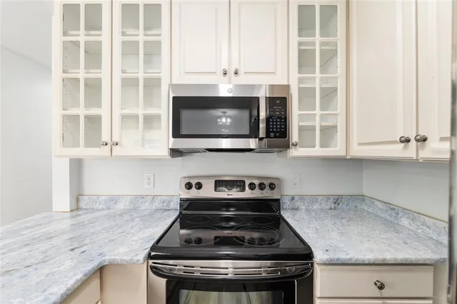 a kitchen with granite countertop a stove a sink and a microwave