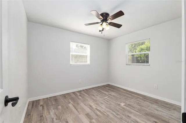 a view of empty room with wooden floor and fan
