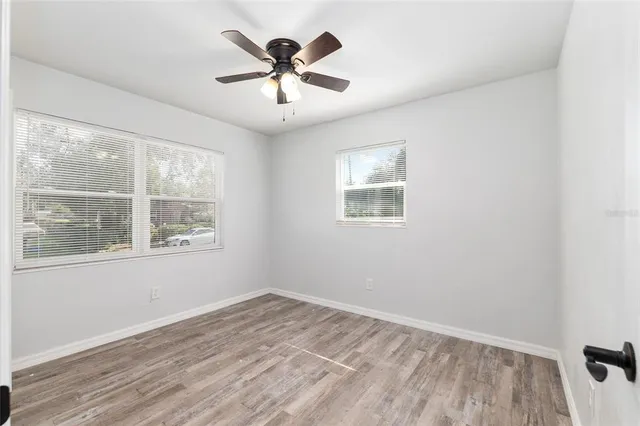 a view of empty room with wooden floor and fan