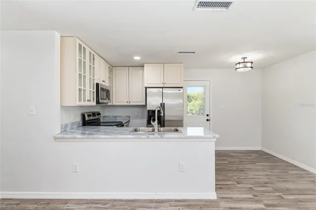 a kitchen with kitchen island granite countertop a sink cabinets and stainless steel appliances