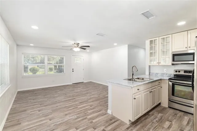 a kitchen with stainless steel appliances granite countertop a sink cabinets and wooden floor
