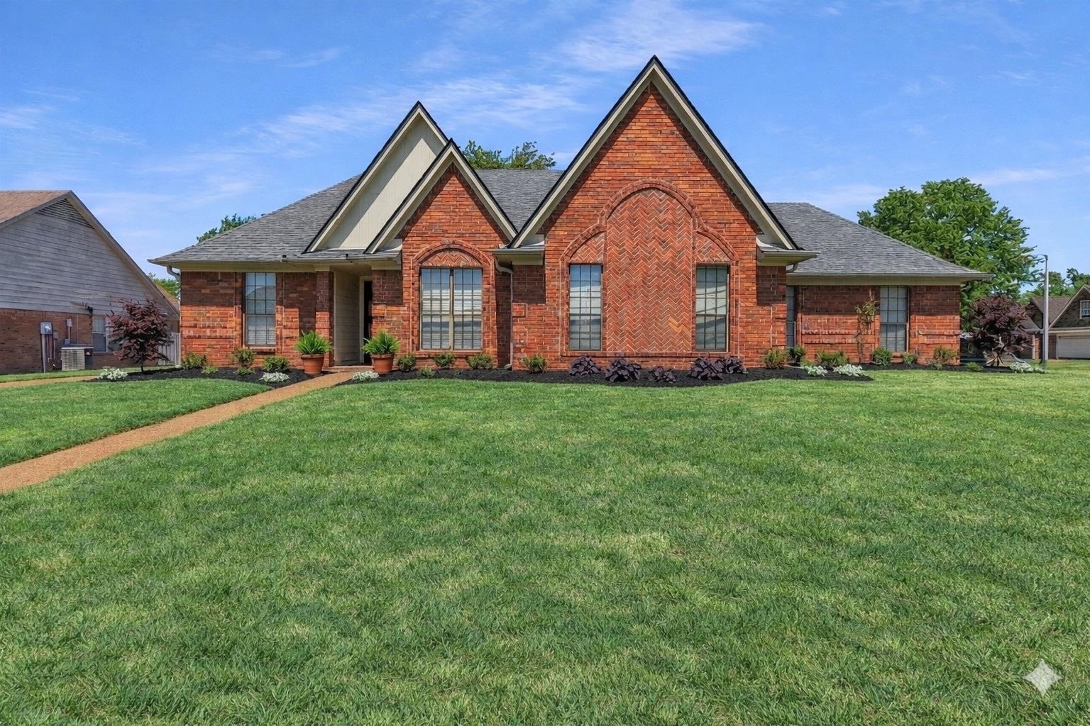 View of front of home with a front yard, brick siding, and roof with shingles