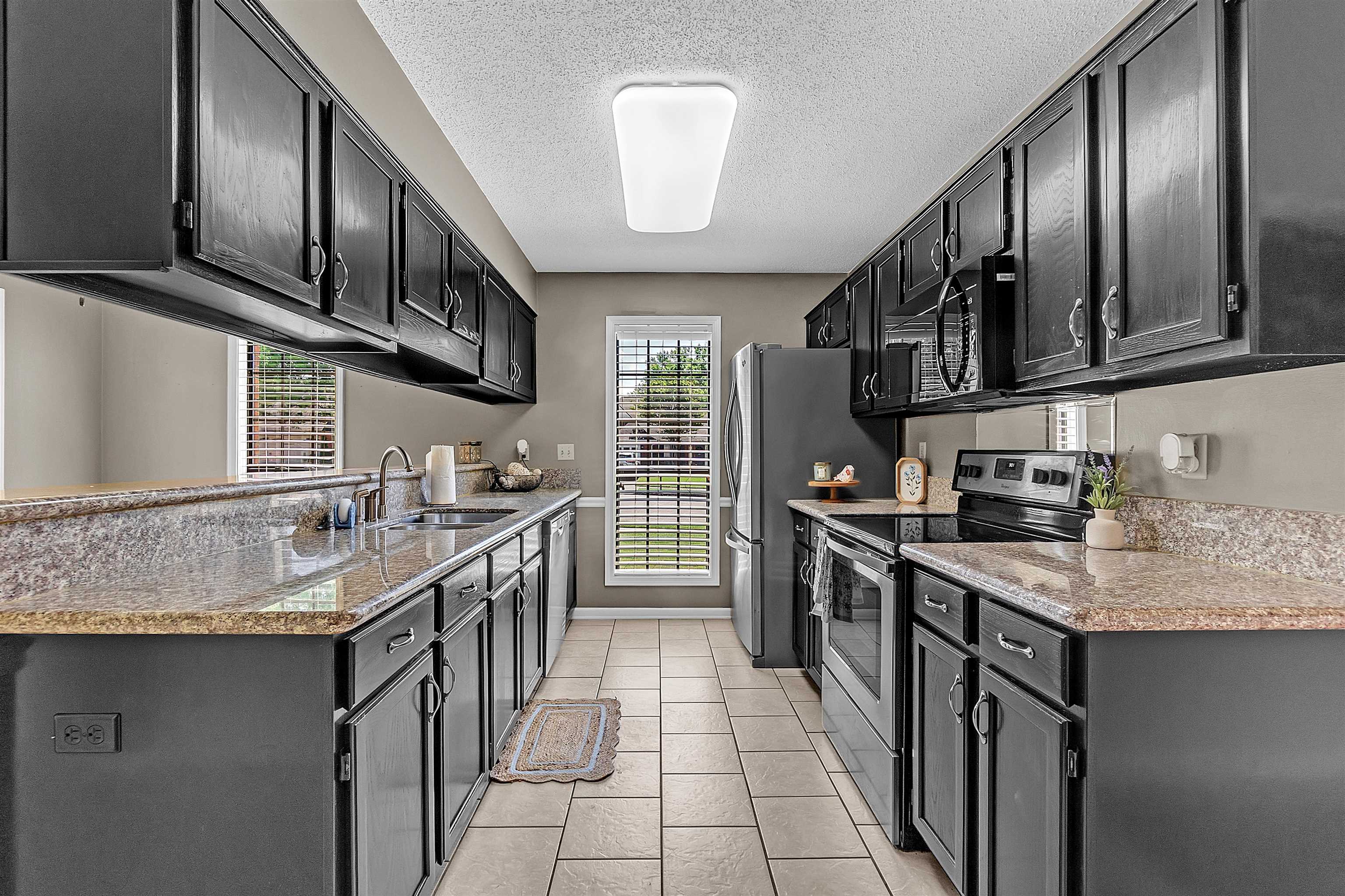 6512 Birch Mill Road Bartlett, TN 38135 - Photo 7 of 25 Kitchen featuring dark cabinetry, stainless steel appliances, light stone countertops, a textured ceiling, and light tile patterned floors
