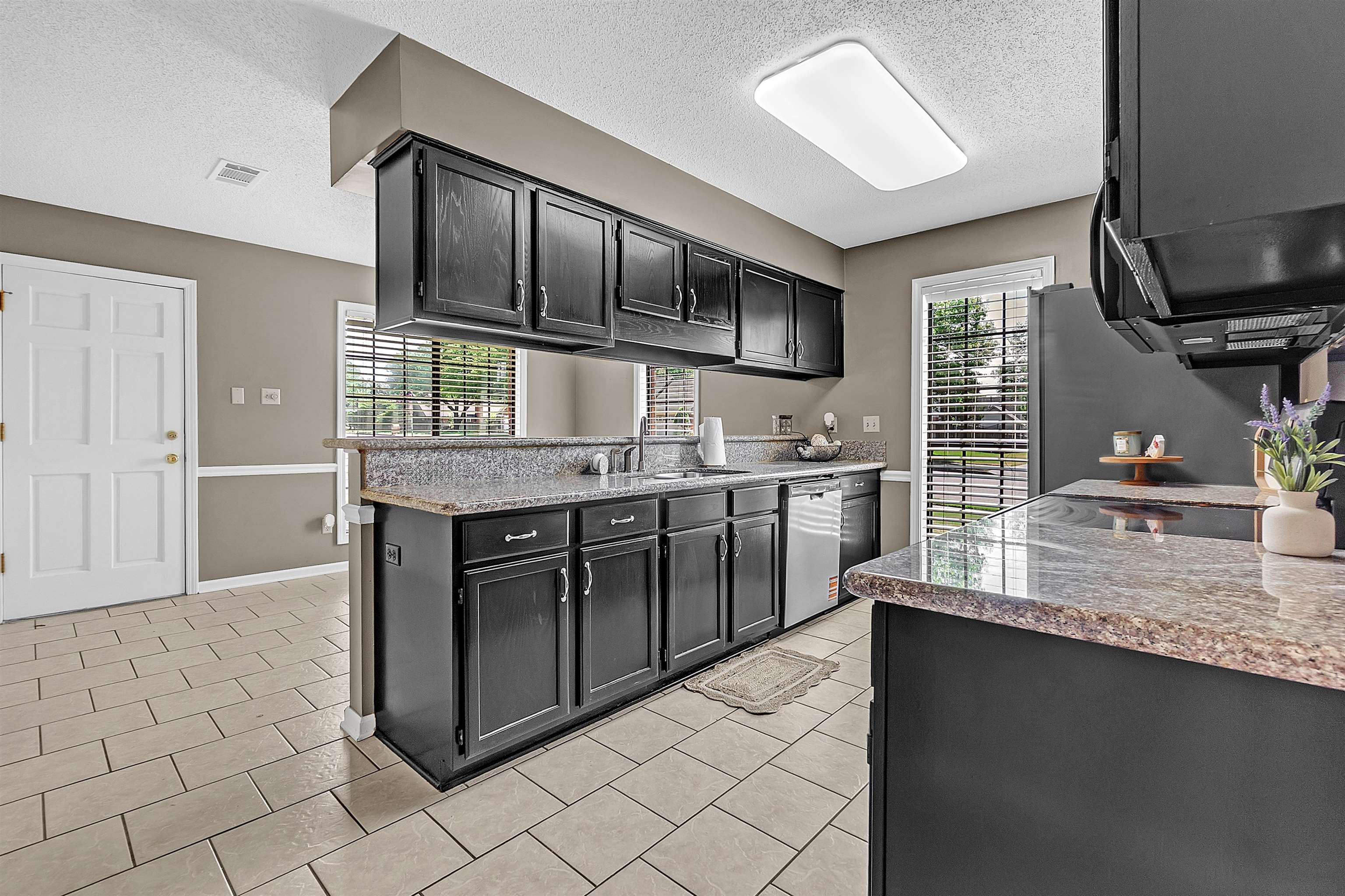 6512 Birch Mill Road Bartlett, TN 38135 - Photo 8 of 25 Kitchen with dark cabinets, a textured ceiling, light stone countertops, stainless steel appliances, and light tile patterned flooring