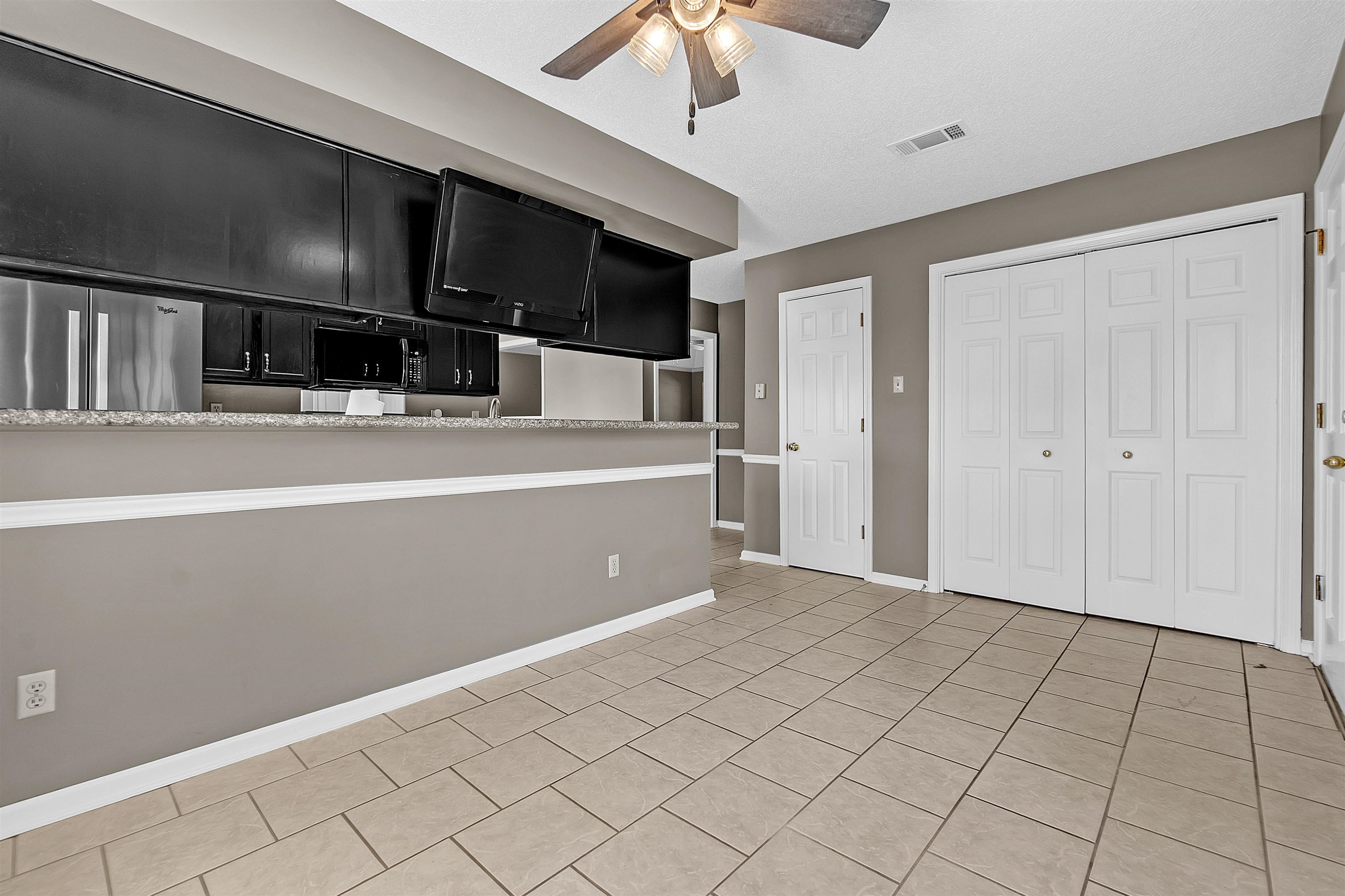 6512 Birch Mill Road Bartlett, TN 38135 - Photo 10 of 25 Kitchen with dark cabinets, ceiling fan, light countertops, stainless steel fridge, and light tile patterned flooring