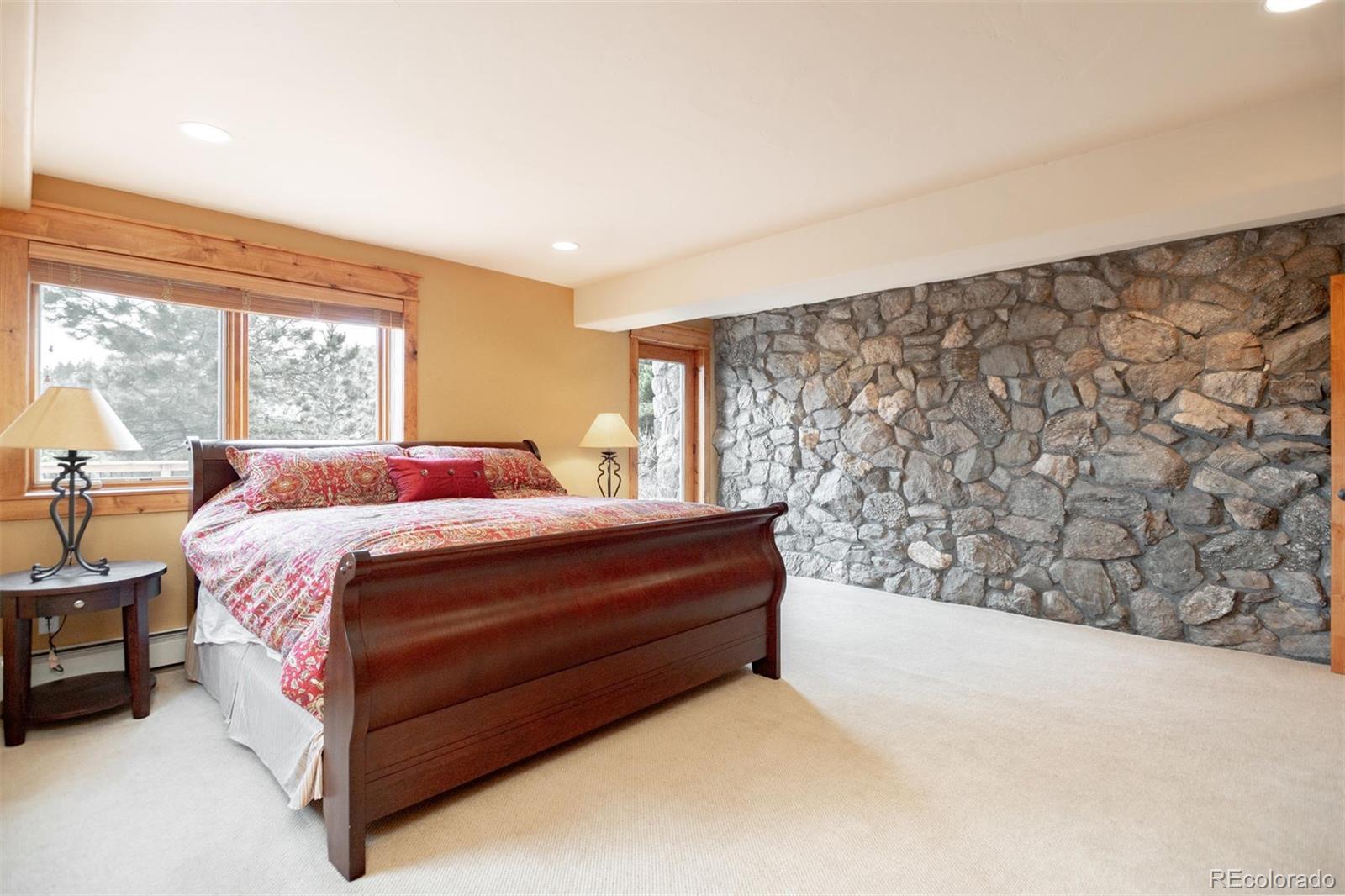 33231 Meadow Mountain Road Evergreen, CO 80439 - Photo 31 of 40 a bed sitting in a spacious bedroom next to a window