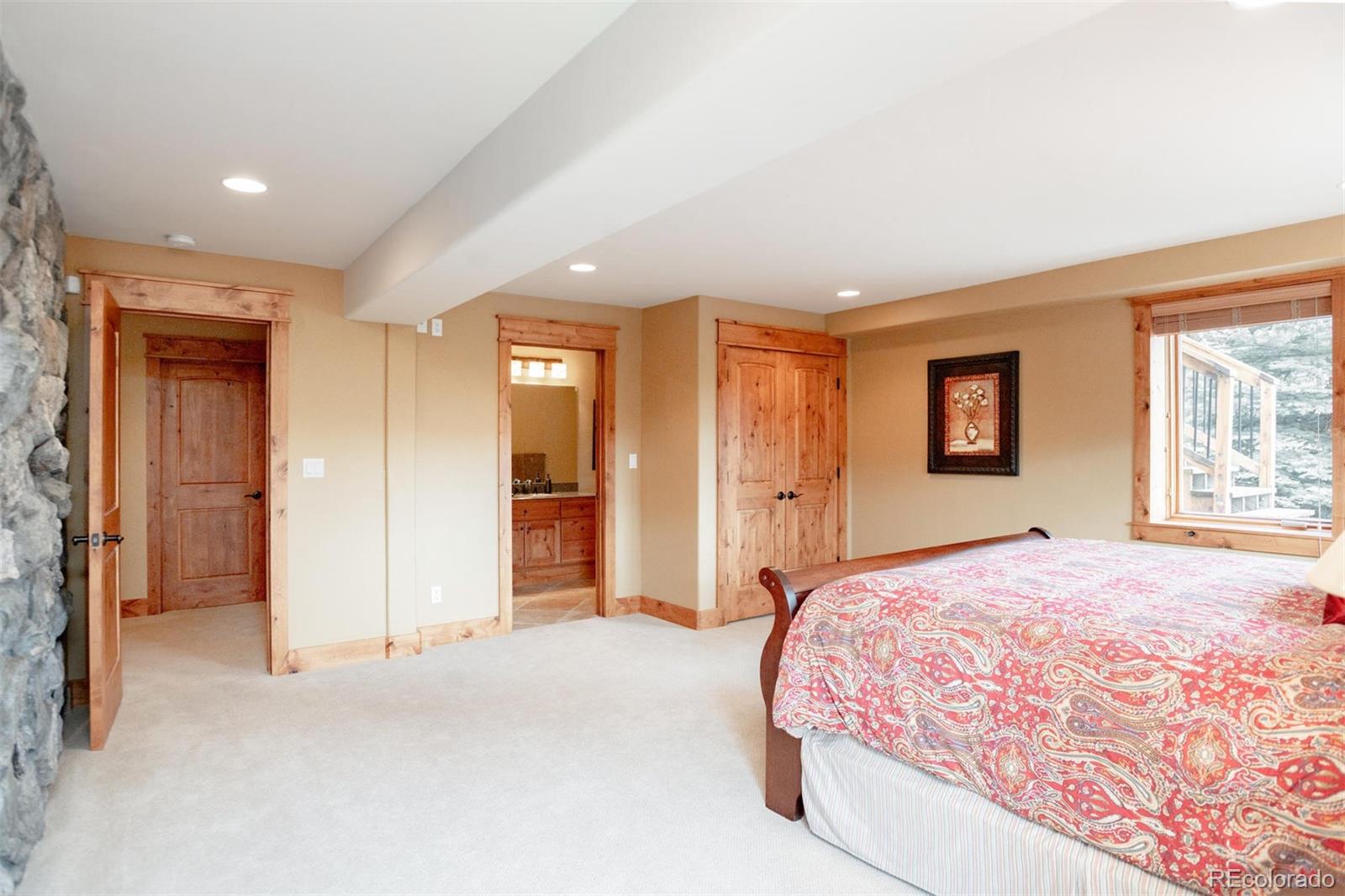 33231 Meadow Mountain Road Evergreen, CO 80439 - Photo 32 of 40 a spacious bedroom with a large bed and a chandelier