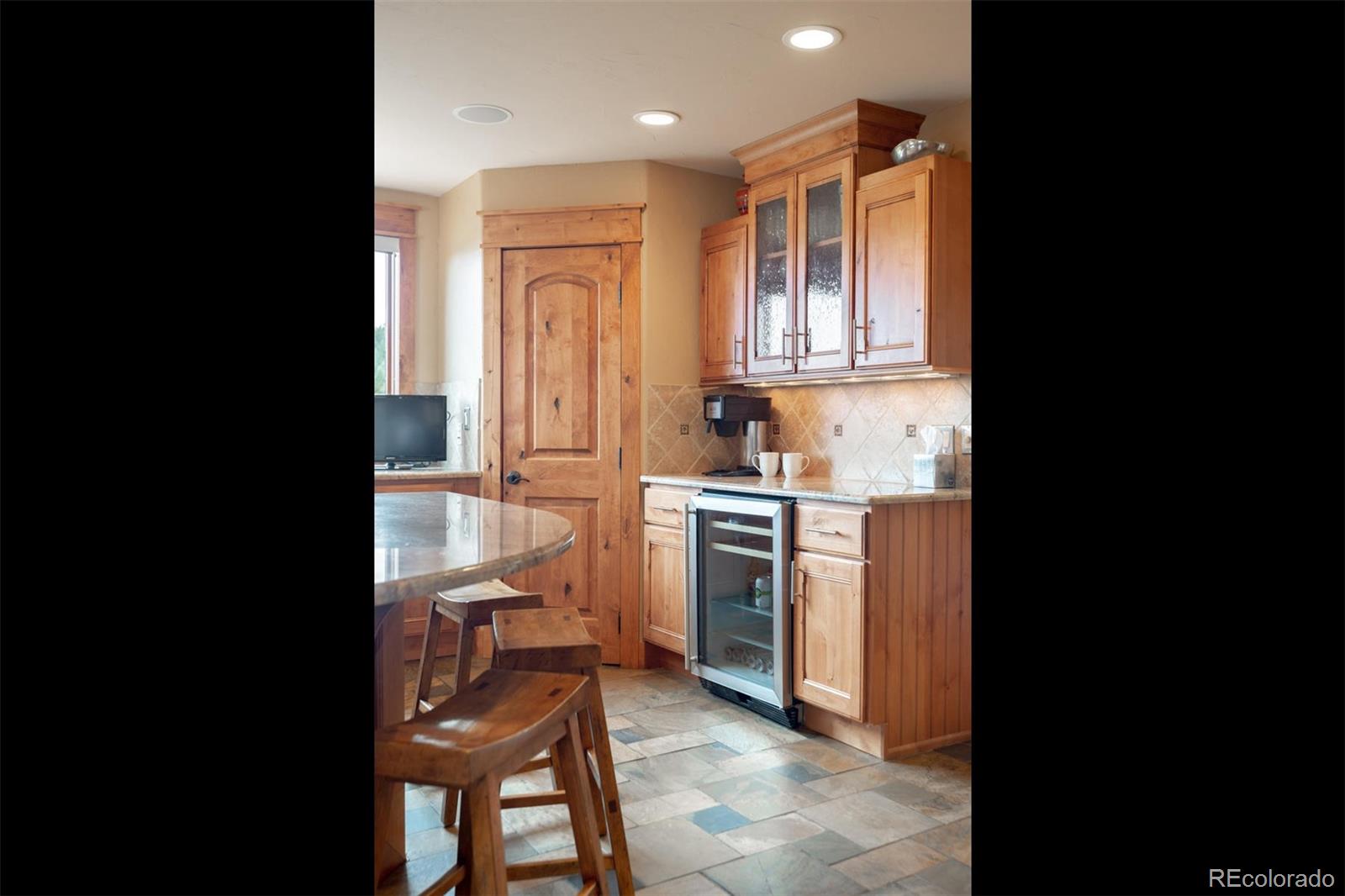 33231 Meadow Mountain Road Evergreen, CO 80439 - Photo 7 of 40 a kitchen with a refrigerator and white cabinets