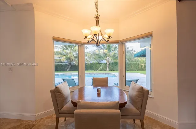 a view of a dining room with furniture large windows and a chandelier
