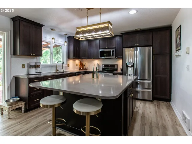 a kitchen with stainless steel appliances a sink a microwave cabinets and wooden floor