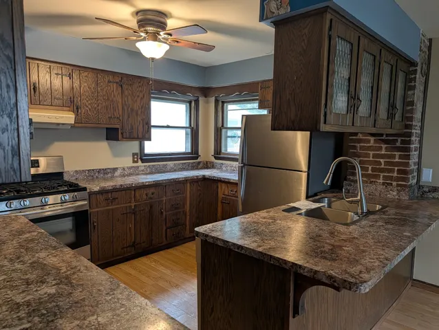 a kitchen with stainless steel appliances granite countertop a refrigerator a sink and a stove