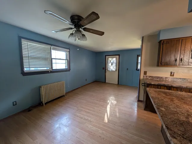 a view of an empty room with window and wooden floor