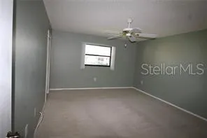 an empty room with windows and fan