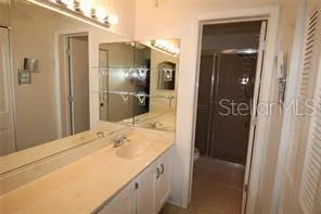 a bathroom with a granite countertop sink a mirror and a shower