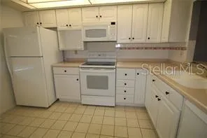 a kitchen with white cabinets and white appliances