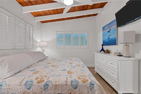 a bedroom with a bed and a flat tv screen on dresser