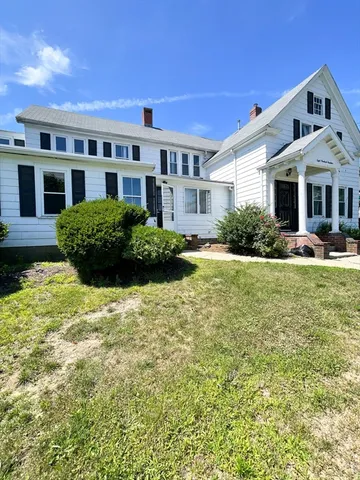 a front view of a building with garden and trees