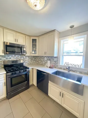 a kitchen with kitchen island granite countertop a stove a sink and a microwave