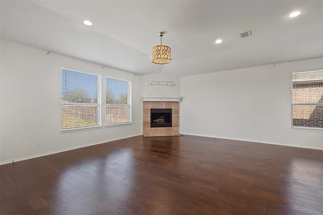 an empty room with wooden floor fireplace and windows
