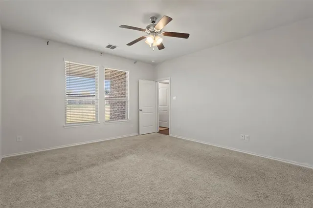 a view of an empty room with chandelier fan and windows