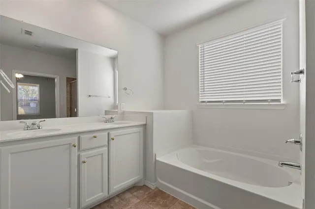 a bathroom with a tub sink and mirror