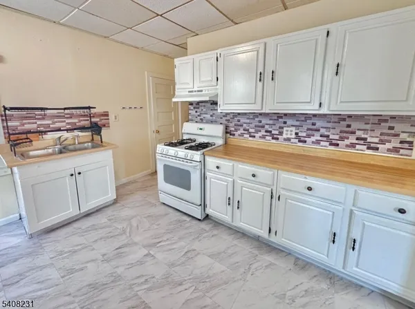 a kitchen with white cabinets sink and stove