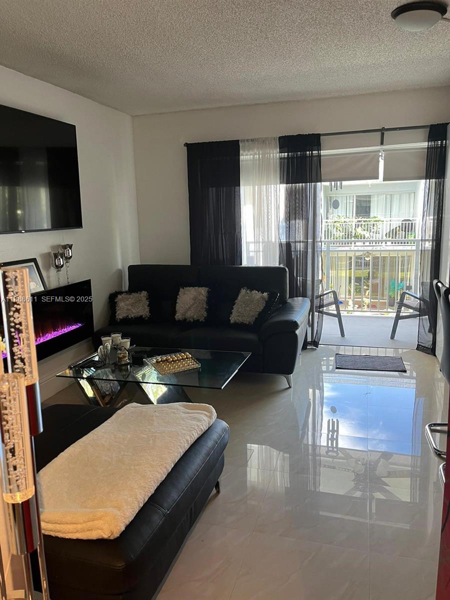 9375 Fontainebleau Boulevard, Unit L219 Miami, FL 33172 - Photo 6 of 13 a living room with furniture and a flat screen tv