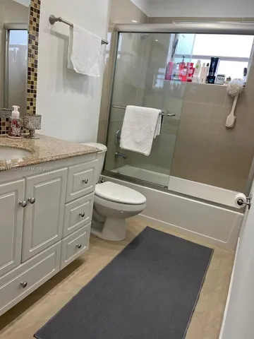 a bathroom with a granite countertop toilet sink and mirror
