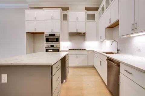 a kitchen with stainless steel appliances granite countertop a sink and dishwasher a stove top oven with white cabinets