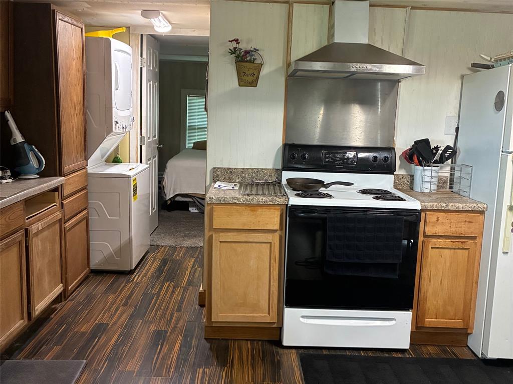 101 County Road 120 C Riesel, TX 76682 - Photo 6 of 7 Kitchen featuring wood-finish flooring, wood cabinetry, laminate countertops, a stainless steel range hood, and a white electric range