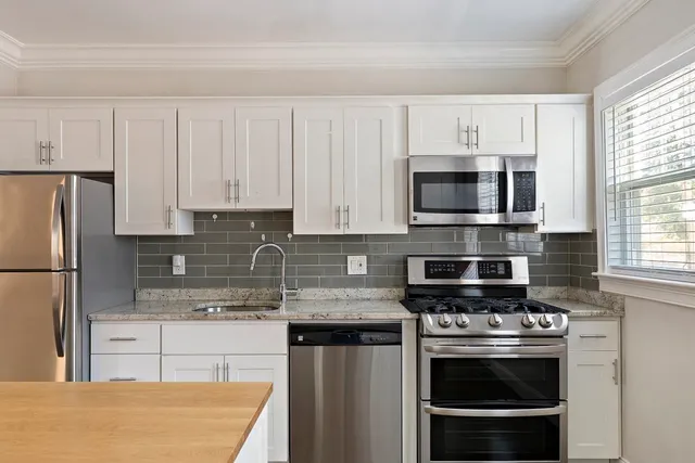 a kitchen with stainless steel appliances granite countertop a stove a refrigerator and a white cabinets