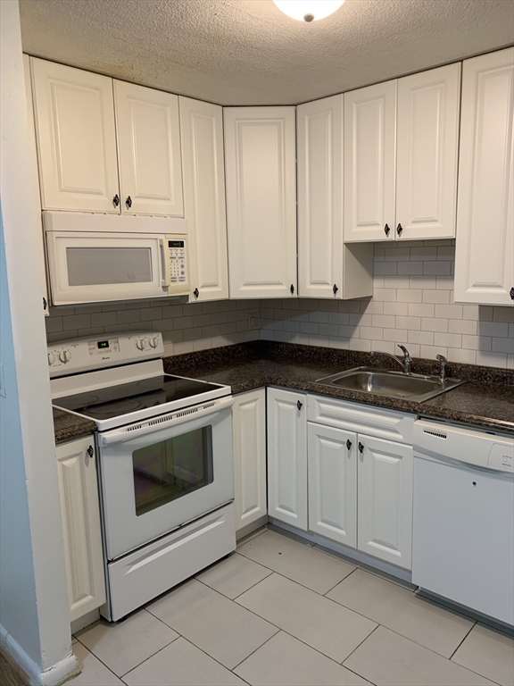 a kitchen with granite countertop white cabinets and stainless steel appliances