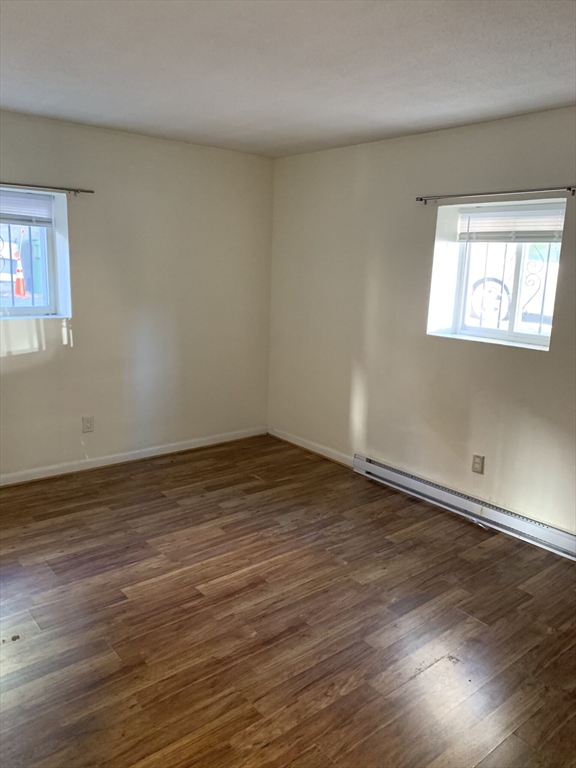 10 Scottfield Road, Unit B3 Boston, MA 02134 - Photo 11 of 15 a view of an empty room with wooden floor and a window