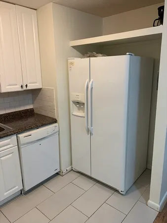 a kitchen with a refrigerator and white cabinets
