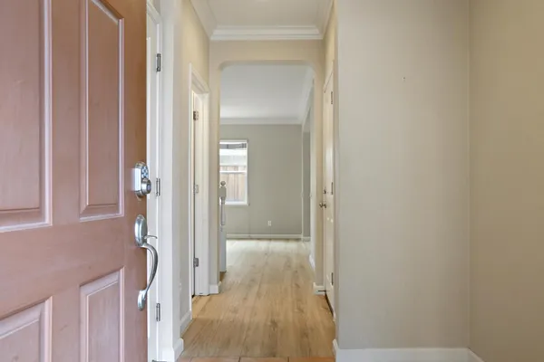 a view of a hallway with wooden floor and a bathroom