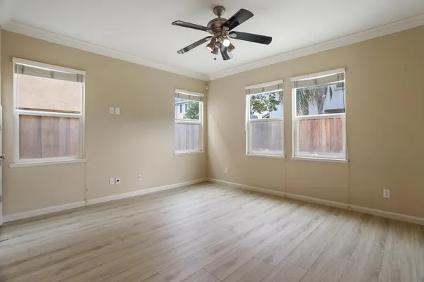 a view of an empty room with a window and wooden floor