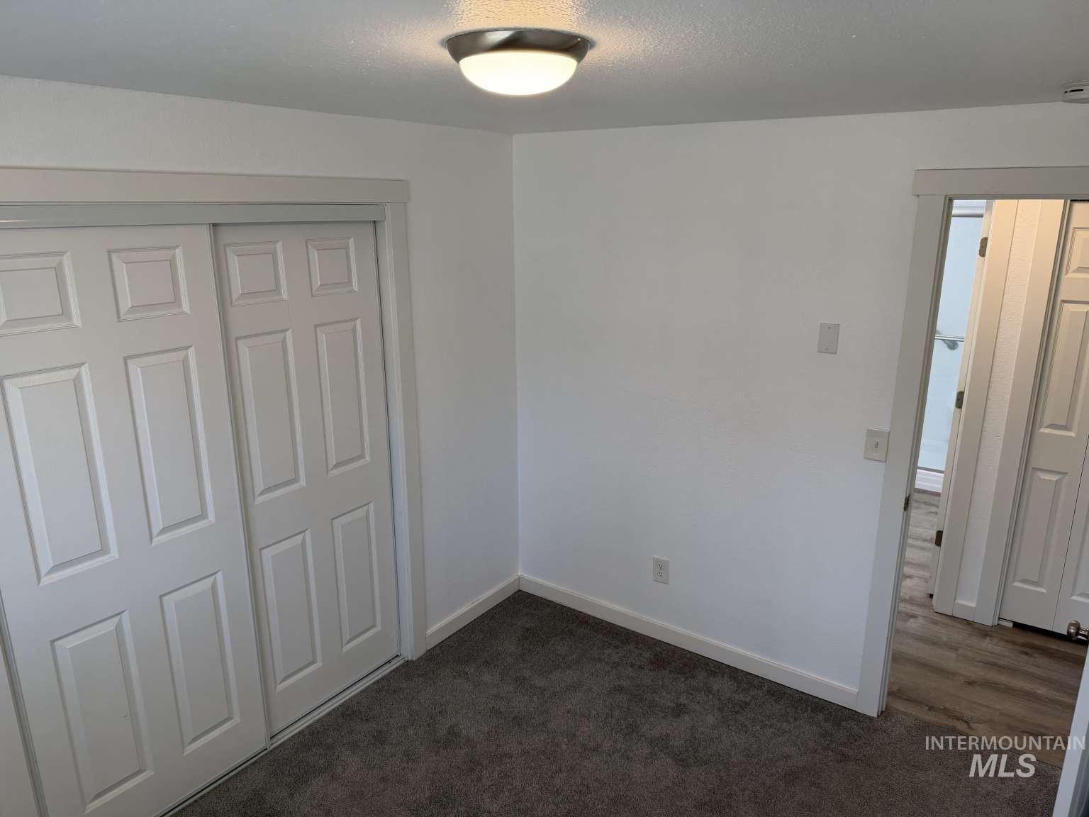 211 Jasper Avenue Middleton, ID 83644 - Photo 11 of 25 Unfurnished bedroom with a closet, dark carpet, and a textured ceiling