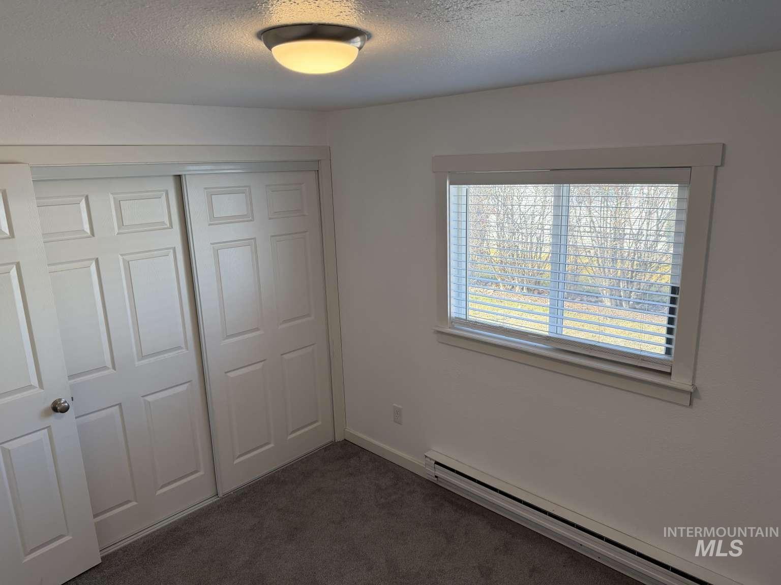 211 Jasper Avenue Middleton, ID 83644 - Photo 13 of 25 Unfurnished bedroom with baseboard heating, dark carpet, a textured ceiling, and a closet