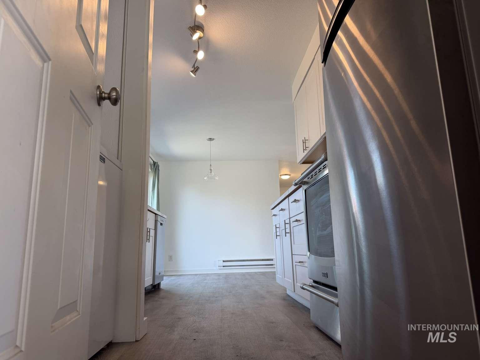 211 Jasper Avenue Middleton, ID 83644 - Photo 17 of 25 Kitchen featuring stainless steel refrigerator, white cabinetry, hanging light fixtures, washer / clothes dryer, and a baseboard heating unit