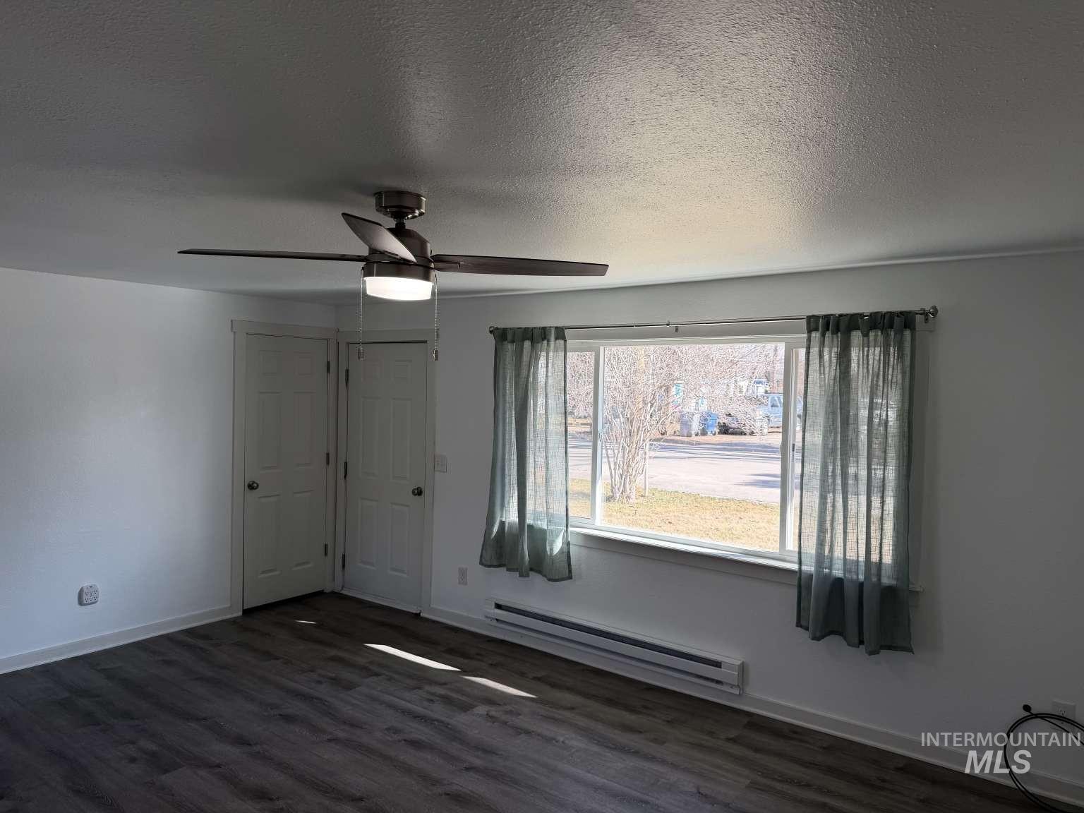 211 Jasper Avenue Middleton, ID 83644 - Photo 18 of 25 Unfurnished bedroom featuring a baseboard heating unit, dark wood-type flooring, a ceiling fan, and a textured ceiling