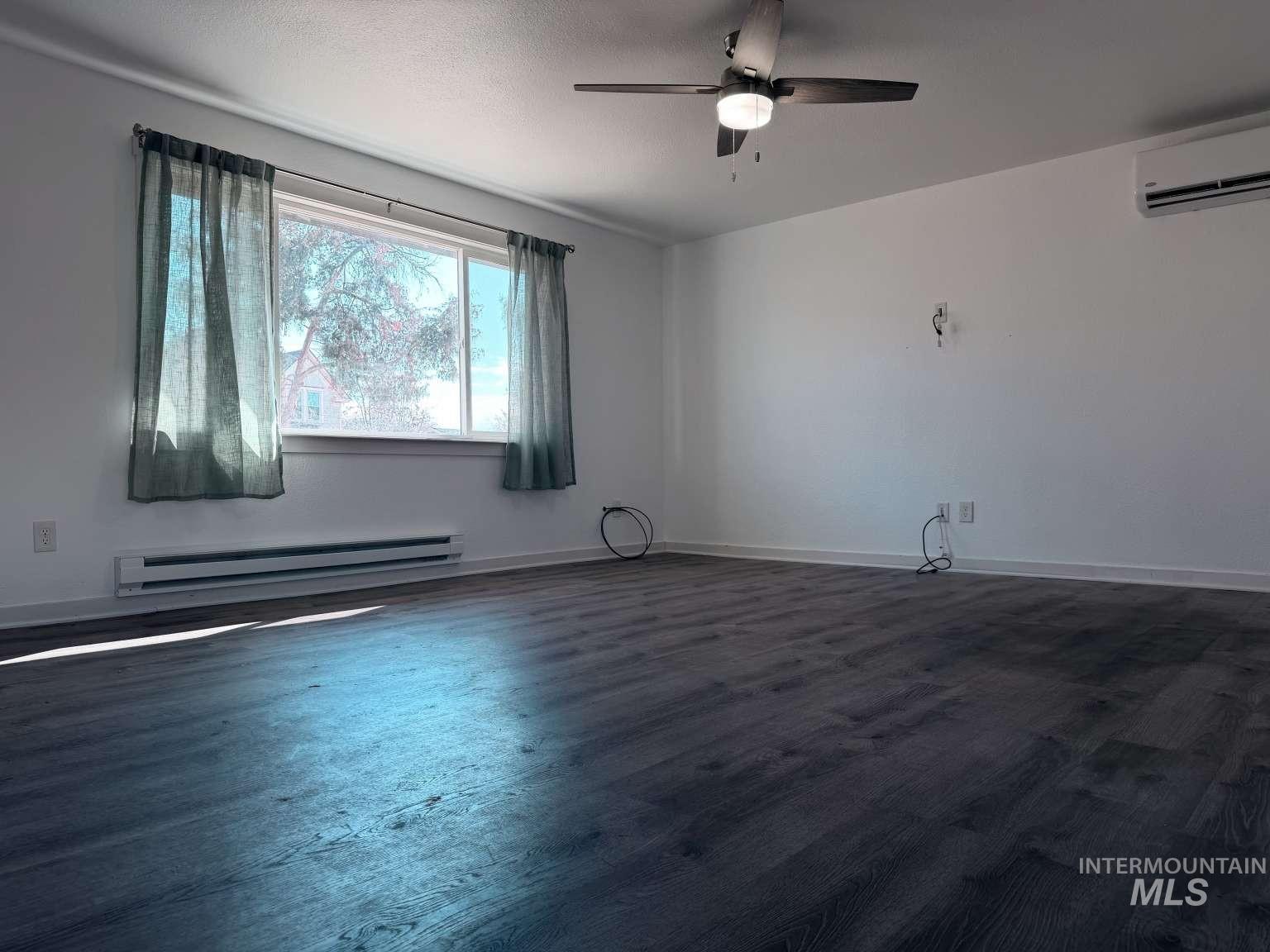 211 Jasper Avenue Middleton, ID 83644 - Photo 5 of 25 Spare room featuring a baseboard radiator, ceiling fan, and dark wood finished floors