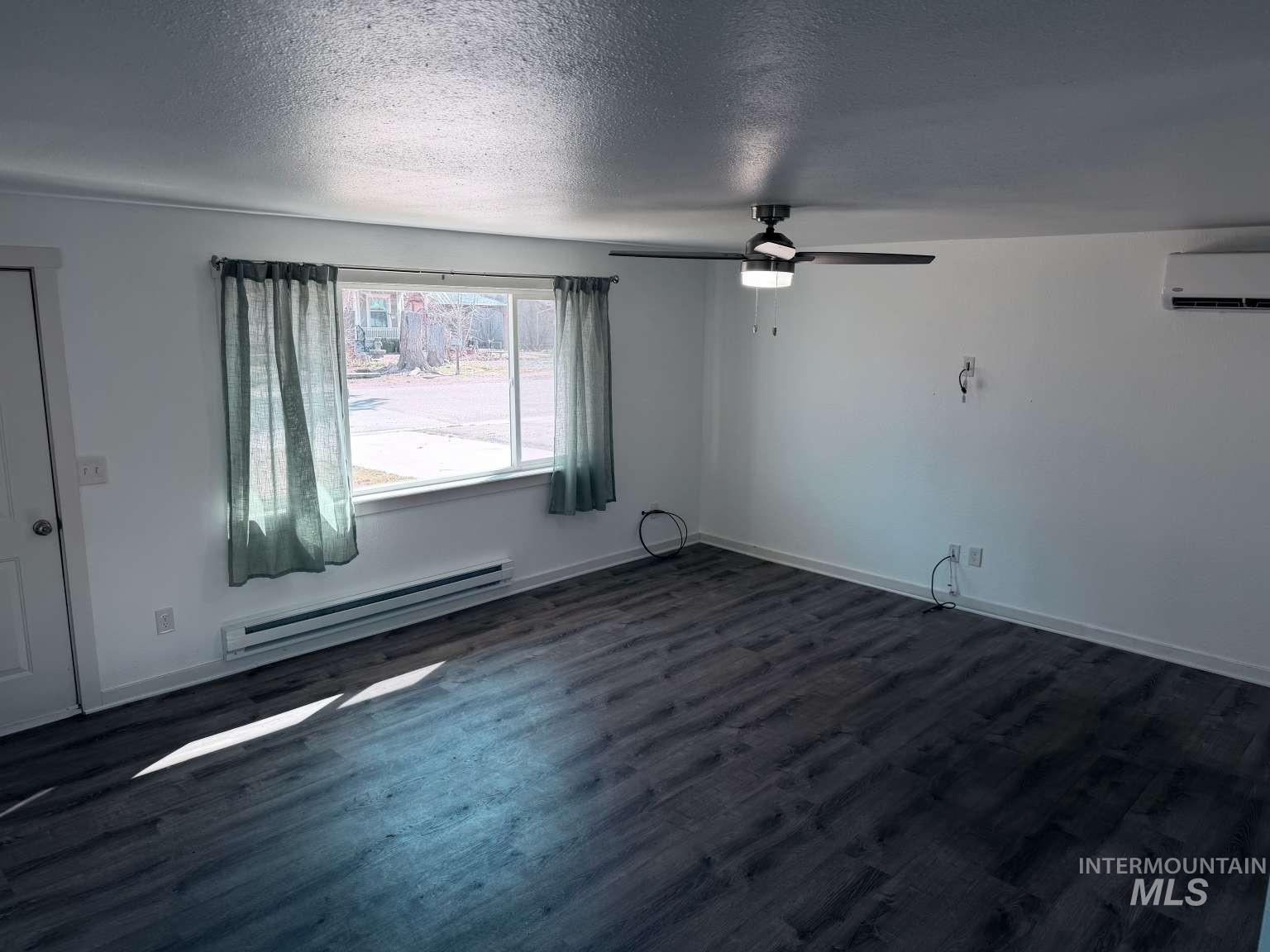 211 Jasper Avenue Middleton, ID 83644 - Photo 6 of 25 Spare room with baseboard heating, a textured ceiling, dark wood-style floors, and a ceiling fan